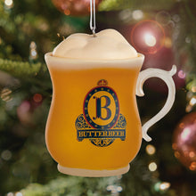 Load image into Gallery viewer, Butterbeer mug ornament hanging on a Christmas tree with festive lights in the background
