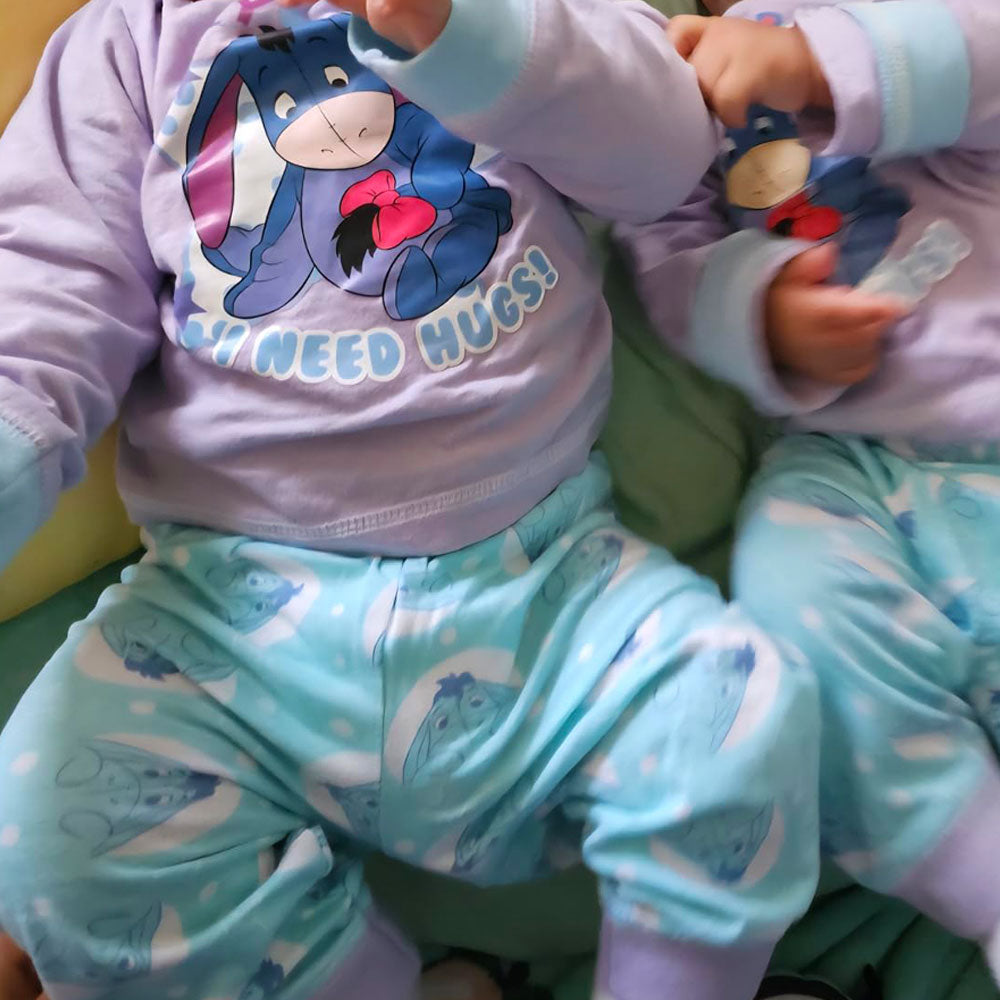 Two children wearing matching Disney Eeyore Baby Toddler Outfits , sitting on a green surface.