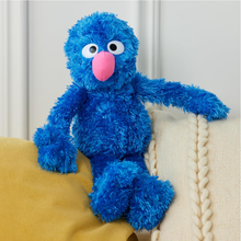 Load image into Gallery viewer, Sesame Street Grover Blue plush toy with a pink nose sitting on a yellow couch.

