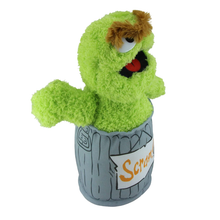 Load image into Gallery viewer, Sesame Street Oscar  Green plush toy resembling a character from Sesame Street, sitting inside a trash can labeled &#39;Scram&#39;.
