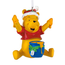 Load image into Gallery viewer, Christmas ornament of a yellow bear in a Santa hat with a blue bucket, on a white background.
