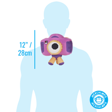 Load image into Gallery viewer, A purple and pink toy camera plush with a large white eye is shown centered on a light blue human silhouette to indicate scale, with text reading 12" / 28cm and a Merchimpo logo in the bottom right.
