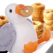 Load image into Gallery viewer, Plush toy seagull holding a donut in mouht in front of a stack of donuts 
