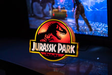 Load image into Gallery viewer, Jurassic Park Logo Light illuminated and sitting in front of tv showing the movie Jurassic Park
