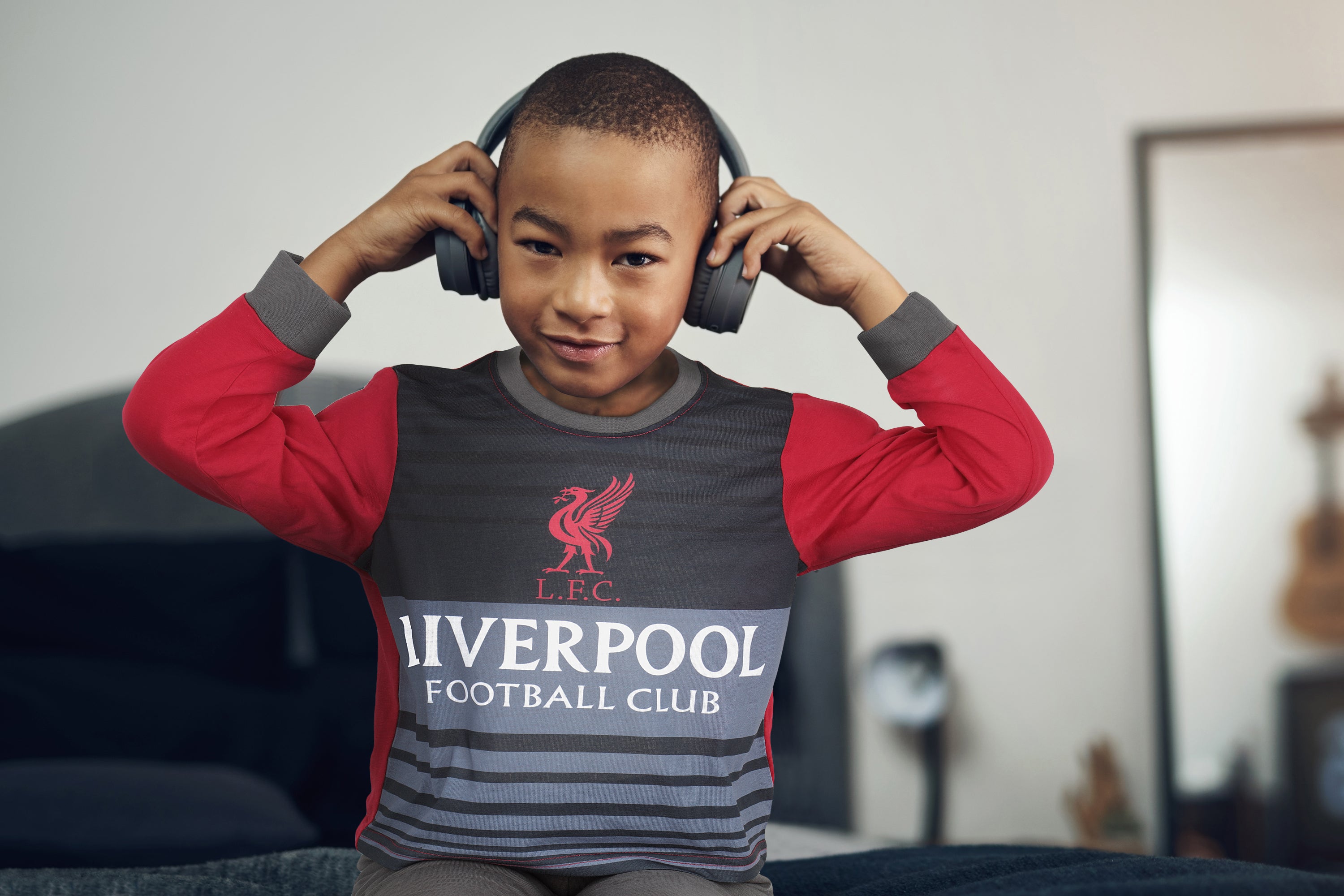 boy aged 7-8 wearing Liverpool FC Pyjamas and listening to music with headphones
