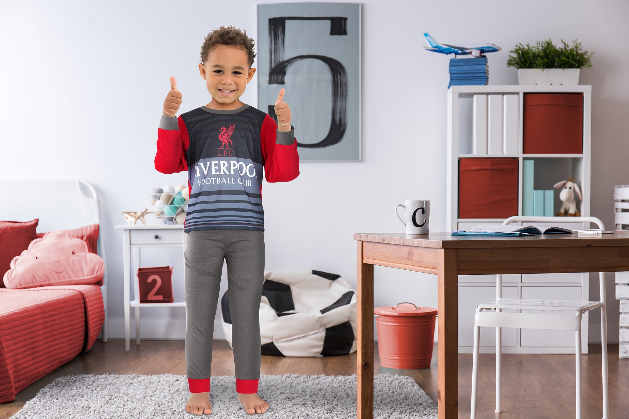 Boy aged 5 standing in bedroom wearing Liverpool FC PJs