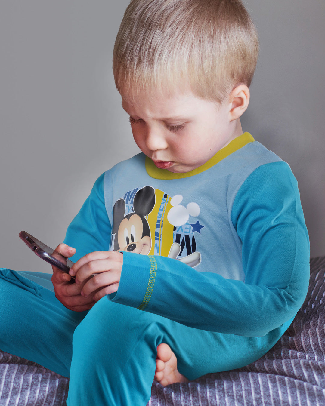 Small Boiy wearing Mickey Mouse Toddler Pyjamas holding mums phone