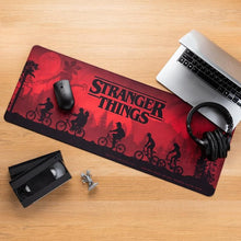 Load image into Gallery viewer, Stranger Things Logo Desk / Gaming Mat on desk with laptop headphones an VHS tape
